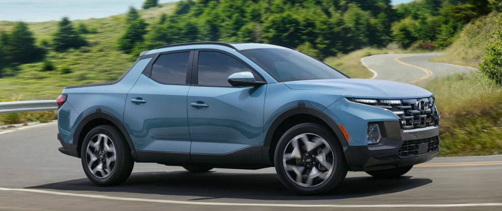 A blue 2024 Hyundai Santa Cruz driving on the road.
