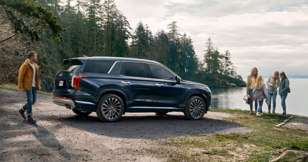 A family hanging out by a lake outside of their Hyundai Palisade