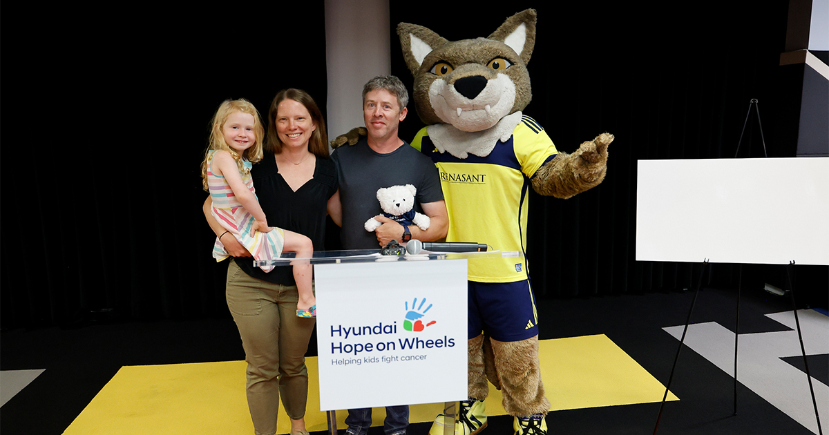 A family and mascot holding up a Hyundai Hope on Wheels sign