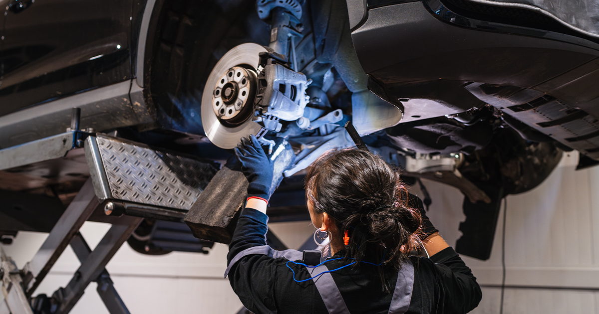 A service technician working on the brakes of a vehicle lifted in the service center.