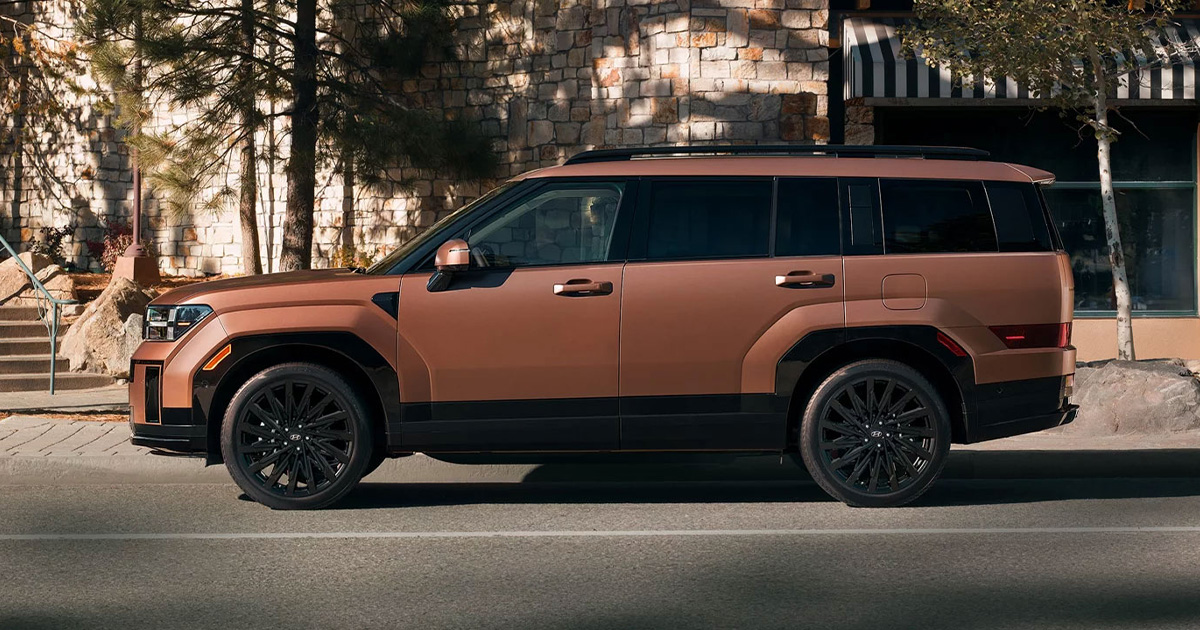 A profile view of an orange Hyundai Santa Fe parked in front of a cafe.